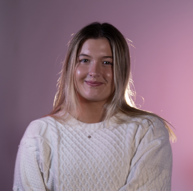 Headshot of Sadie Grunau, smiling in a white sweater.