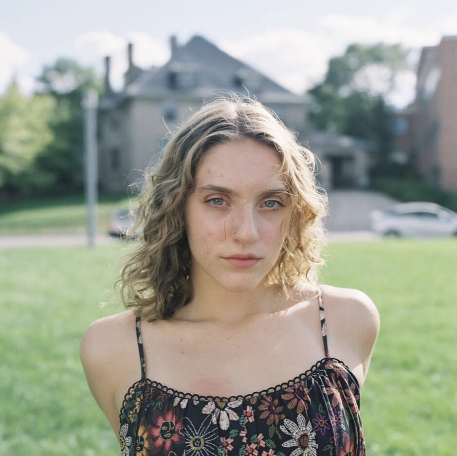 Headshot of Maya Modelli, looking straight ahead in a flowered blouse.