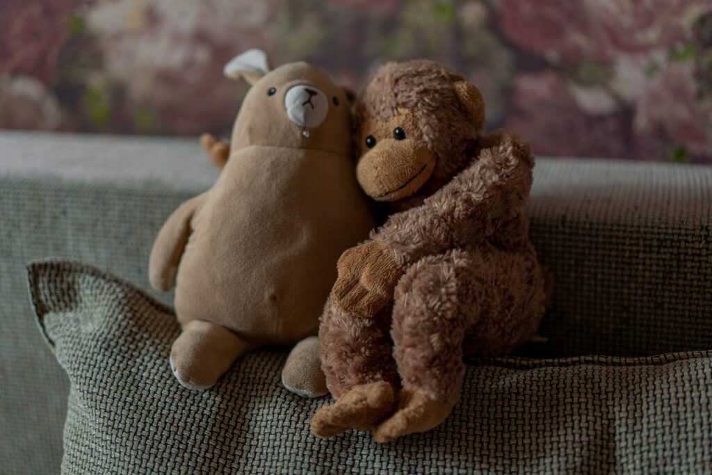 Photo of two brown stuffed animals hugging on a pillow