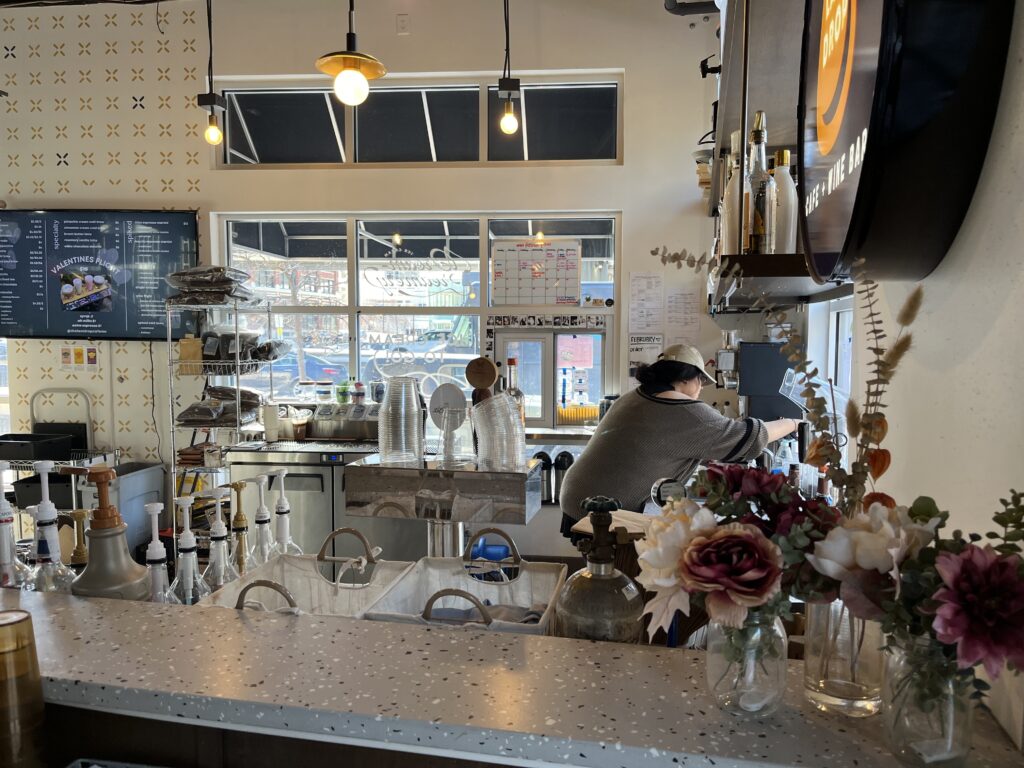 Interior of a coffee shop with a barista working behind the counter.